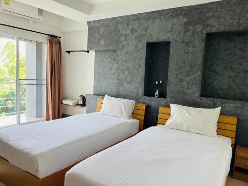 a hotel room with two beds and a window at Pilatus Apartment in Loei