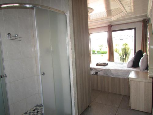 ein Bad mit einer Dusche und ein Bett mit einem Fenster in der Unterkunft Kea-Resort in Hammanskraal next to Dinokeng Game Reserve in  Hammanskraal 