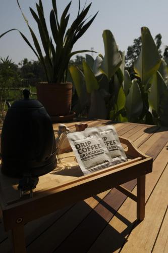 a wooden table with a pot and a newspaper on it at บ้านนาก๋างโต้ง Baan Na Kang Tong in Ban Kot