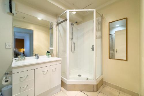 uma casa de banho branca com um chuveiro e um lavatório. em Two bedrooms Condo with Skytower View em Auckland