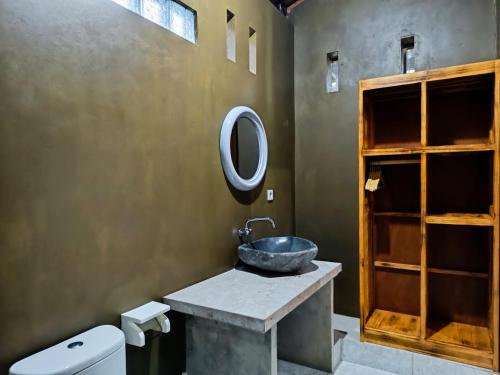 ein Bad mit einem Waschbecken und einem Wandspiegel in der Unterkunft Artomoro Bali in Munduk