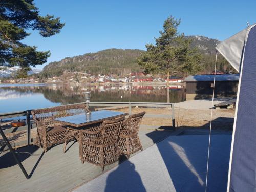 a table and chairs on a deck next to a lake at Nedre Strand Hytteutleie in Vradal