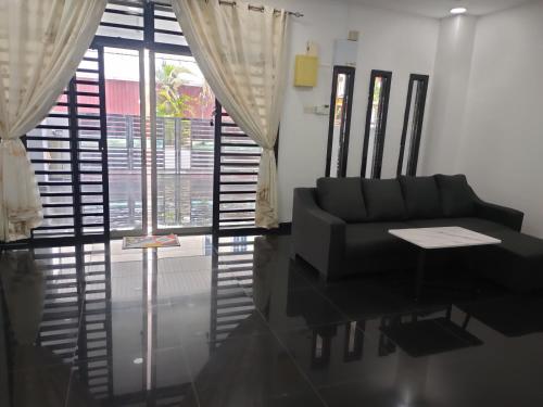 a living room with a black couch and a window at ankang in Alor Setar