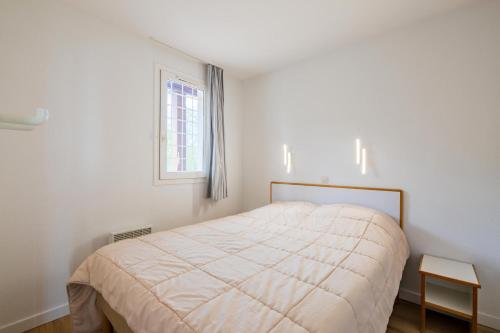 une chambre blanche avec un lit et une fenêtre dans l'établissement Résidence le Hameau de Cap Esterel - maeva Home - Appartement 2 Pièces 7 Personnes - Sélection MAE-8711, à Saint-Raphaël