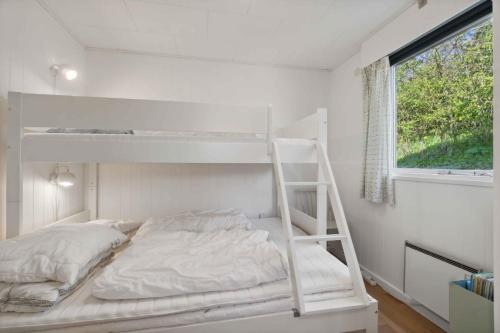 a white bunk bed in a white room with a window at Idyllic Holiday Home Near Cliffs And Beach in Gudhjem