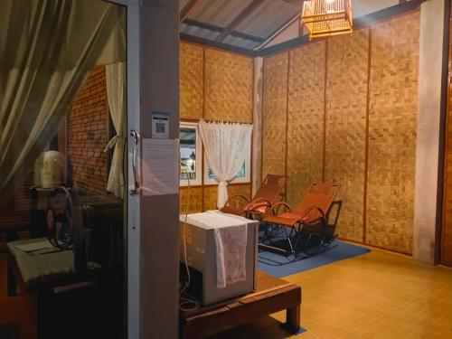 uma sala de estar com cadeiras e uma televisão numa mesa em แม่อุ๊ยโฮมสเตย์&mae uai homestay em Ban Pok Nai
