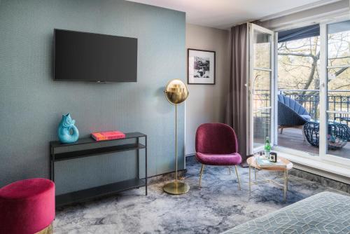 ハンブルクにあるHotel du Nordの壁にテレビと椅子2脚が備わる客室です。