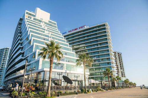 a large building with palm trees in front of it at Marina Batumi Sea View in Batumi