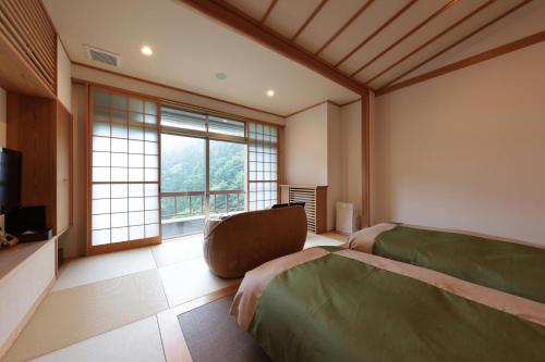 a bedroom with two beds and a tv and a window at Akagi Onsen Hotel in Maebashi