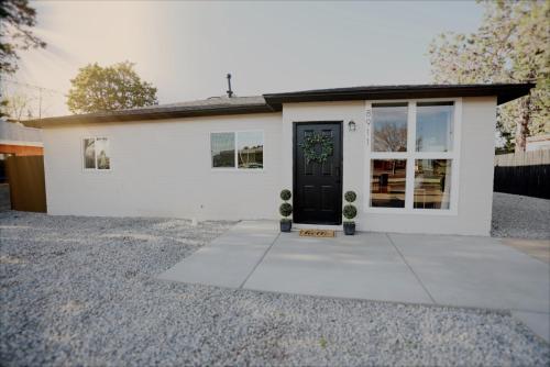 a white house with a black door at The White House-NEWLY REMODELED & CENTRALLY LOCATED! in Albuquerque