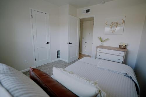 a white bedroom with a bed and a dresser at Centrally Located! Remodeled! Huge Backyard! The White House in Albuquerque