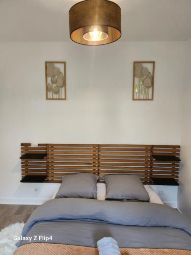 une chambre avec un grand lit avec une tête de lit en bois dans l'établissement Hébergement, Au couché du soleil, à Lannion