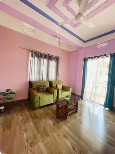 a living room with a green couch and pink walls at Renade Leisure Stay in Agartala