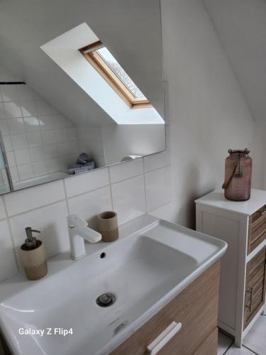 a bathroom with a white sink and a skylight at Hébergement, Au couché du soleil in Lannion