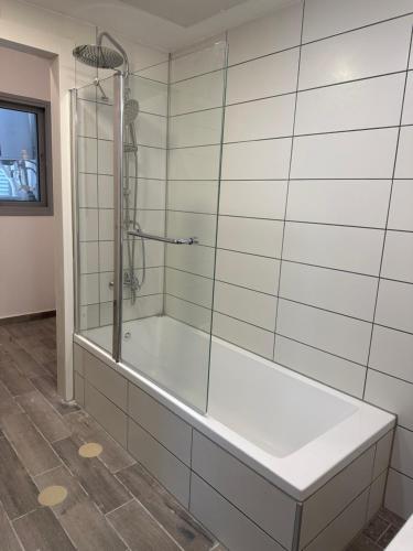 a glass shower in a bathroom with a tub at SkyHostel_32Floor in Netanya