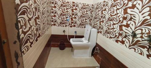 a bathroom with a toilet in a room with wallpaper at OYO Home Anandi Homestay in Ayodhya