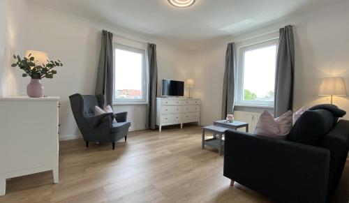 a living room with a couch and chairs and two windows at Villa Rosalie Sassnitz in Sassnitz