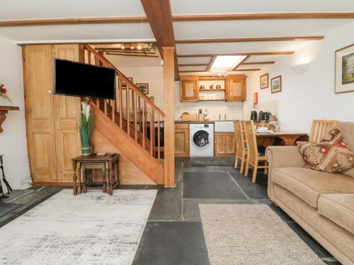 a living room with a couch a table and a kitchen at Mole Cottage in Liskeard