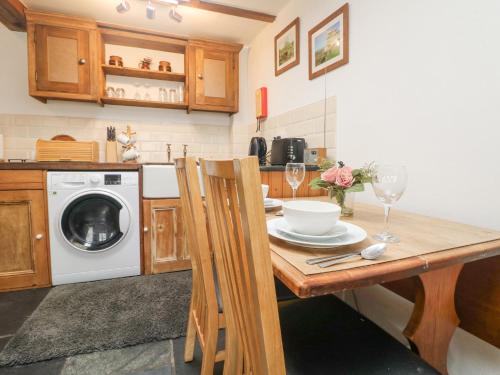a kitchen with a table and a washing machine at Mole Cottage in Liskeard