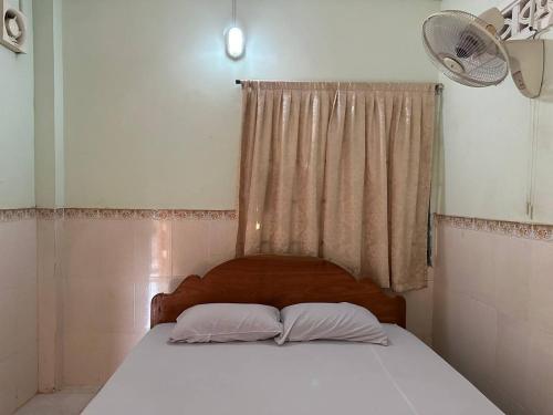 馬德望的住宿－Palm Tree Quest House，一间卧室配有带两个枕头的床和窗户