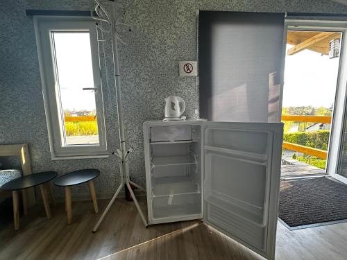 a white refrigerator in a room with two windows at ILSA camping in Bauska