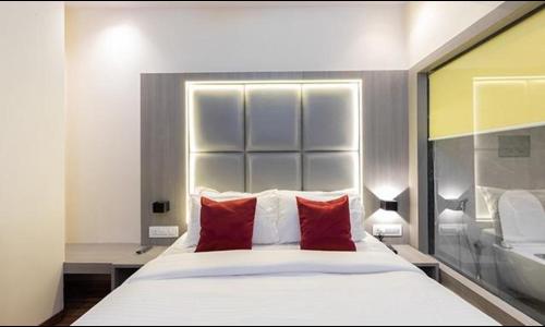 um quarto com uma grande cama branca com almofadas vermelhas em FabHotel Green House em Mumbai