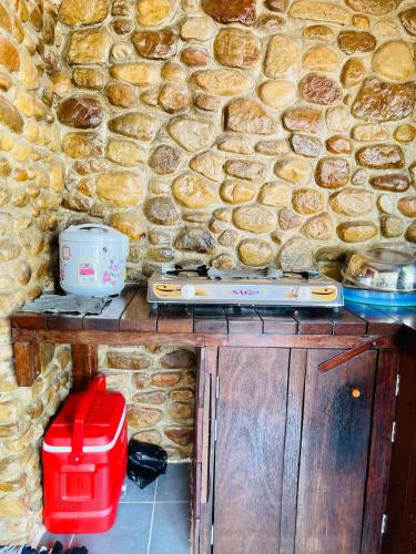 a stoneicked wall with a table with a machine at Wooden house 2 Beds 1 BR 1KCH 1 Dinning Area in Kampot