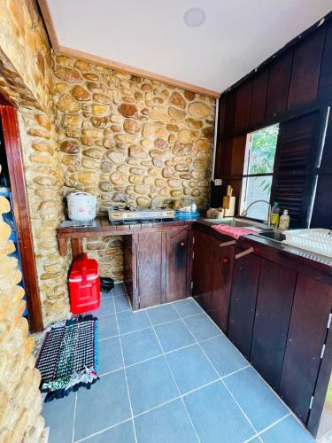 una cocina con armarios de madera y una pared de piedra. en Wooden house 2 Beds 1 BR 1KCH 1 Dinning Area en Kampot