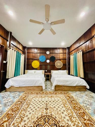 1 dormitorio con 2 camas y ventilador de techo en Wooden house 2 Beds 1 BR 1KCH 1 Dinning Area, en Kampot