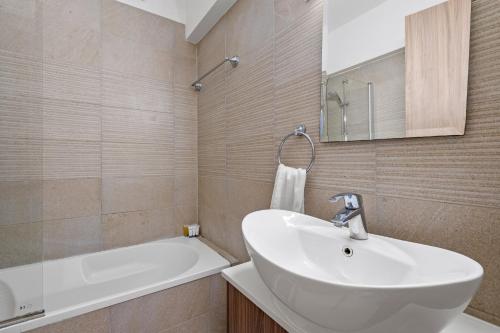 a bathroom with a white sink and a bath tub at Downtown 2 Bedroom Apartment in Larnaka