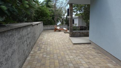a patio with a bench next to a wall at Sweet house with garden 35 meters from sea in Karlobag