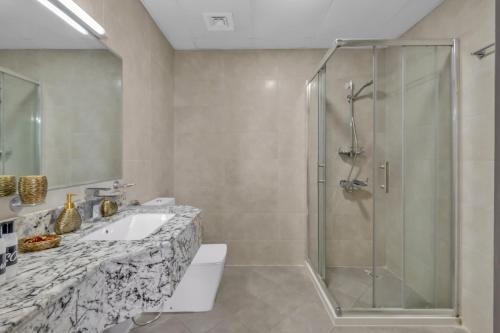 a bathroom with a shower and a sink at Stylish 2BR for 6 with King Beds, Pool, Gym in JVC in Dubai