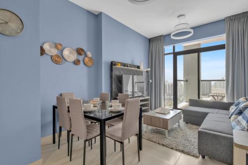 a dining room and living room with a table and chairs at Stylish 2BR for 6 with King Beds, Pool, Gym in JVC in Dubai