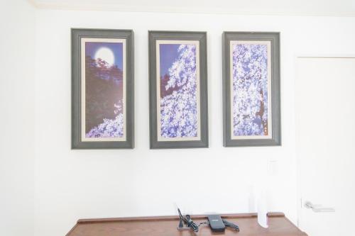 three framed photographs on a wall with a table at Tokyo Private House 大塚の宿 in Tokyo