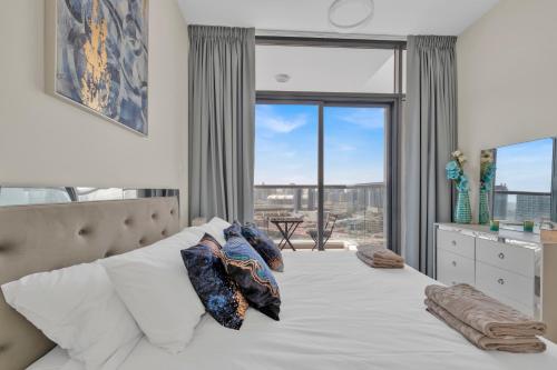 a bedroom with a bed with a large window at Stylish 2BR for 6 with King Beds, Pool, Gym in JVC in Dubai