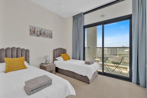 a bedroom with two beds and a balcony at Stylish 2BR for 6 with King Beds, Pool, Gym in JVC in Dubai
