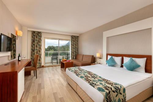 a hotel room with a large bed and a desk at Greenwood Kemer Resort in Kemer