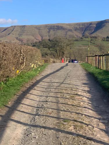 a dirt road with a fence and mountains in the background at Black Mountain Family Room in Velindre