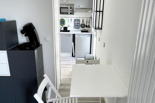 - une cuisine blanche avec une table et une chaise blanches dans l'établissement Studio avec balcon et parking!, à Puilboreau