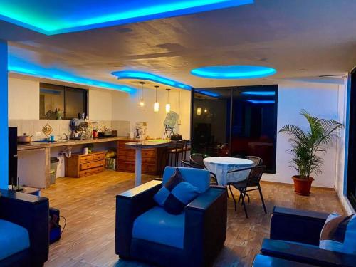 a living room with a couch and a kitchen with blue lights at Villa Mirlo – Escondite de Lujo en Quito in Quito