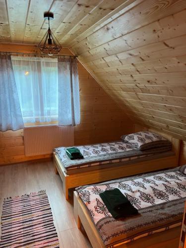 a bedroom with two beds in a log cabin at Leśne Zacisze in Ochotnica Górna