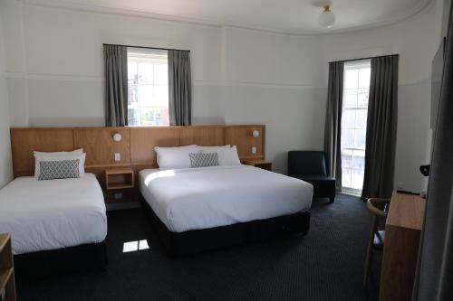 een hotelkamer met 2 bedden en een stoel bij Mortdale Hotel in Mortdale