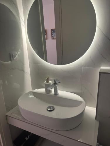 W białej łazience znajduje się umywalka i lustro. w obiekcie Iliana's apartment 2 w mieście Kardítsa