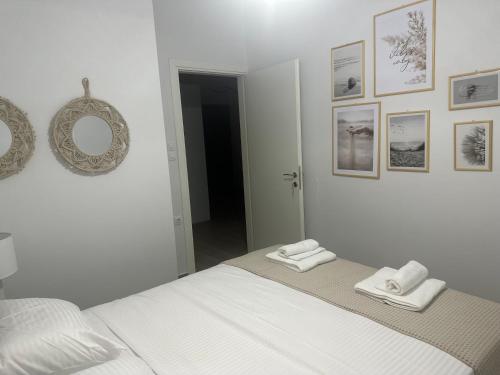 - une chambre blanche avec un lit et des serviettes dans l'établissement Iliana's apartment, à Karditsa