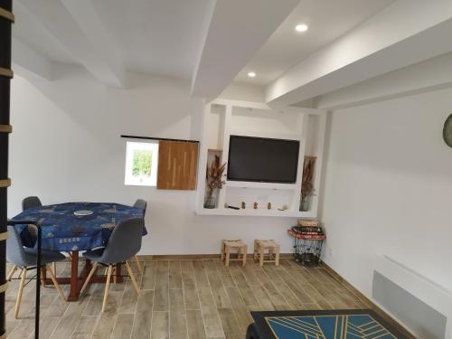 a dining room with a table and a tv on a wall at Maison entre Dinan et Dinard in Pleslin-Trigavou
