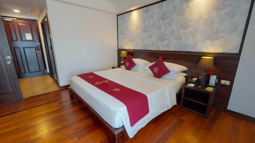 a bedroom with a large white bed with red pillows at Tara Angkor Hotel in Siem Reap
