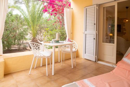 a porch with a table and chairs and a window at Bungalows Casa Amarilla in Playa Migjorn