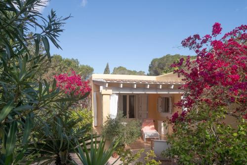 a house with pink flowers in front of it at Bungalows Casa Amarilla in Playa Migjorn