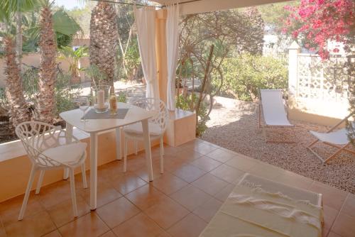 a patio with a white table and chairs and trees at Bungalows Casa Amarilla in Playa Migjorn