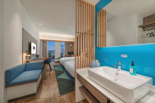 a bathroom with a sink and a bed in a room at Holiday Inn Express Qingdao Chengyang Central, an IHG Hotel in Qingdao